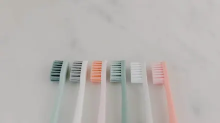 A dog toothbrush resting next to a tube of pet toothpaste on a counter