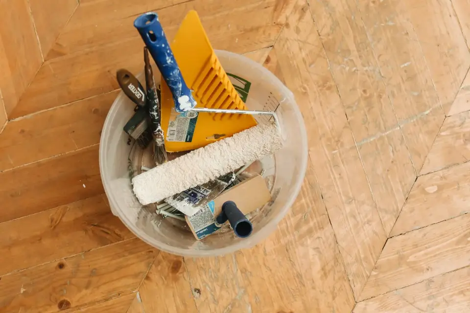 A slicker brush resting on a wood floor near a dog&#x27;s paw